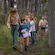 A National Parks Guide leading a group of children down a trail through some trees